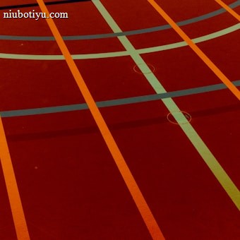 A sports court with intersecting lines in orange and blue, creating geometric patterns on a reddish-brown surface.